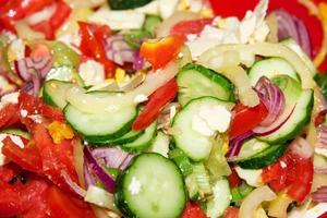 Close-up of fresh salad with cucumber, tomatoes, onions, peppers and cheese photo