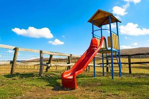 Playground at countryside with a red slide and rural background photo