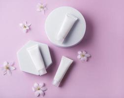 White tubes of cream on a pink background photo