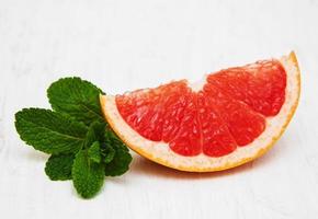 Grapefruit with mint and ice on an old white wooden background photo