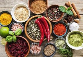 A selection of various colorful spices on a wooden table in bowls and spoons photo