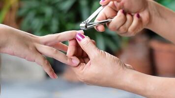 Primer plano una mano de mujer está utilizando un cortaúñas para cortar las uñas de un niño video