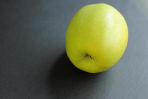 Manzana cruda verde sobre fondo negro foto