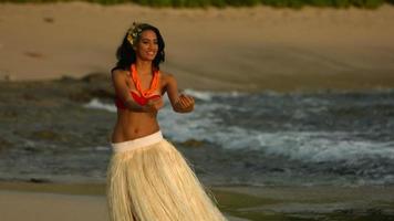 Polynesian hula dancer performs by ocean, slow motion video