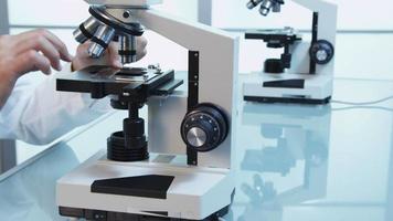 scientifique se penche sur le microscope, le mouvement du chariot video