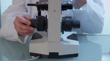 Female scientist looks into microscope video