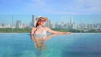 mulher relaxando em uma piscina em frente a uma paisagem urbana video