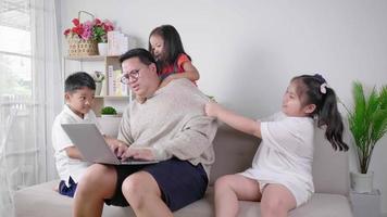 Tired Dad with two girls and a boy trying to bother their father laptop during quarantine Stay at home concept Online working and looking after the kids at the same time while working from home video