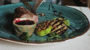 close-up filmando carne assada e vegetais grelhados com molho vermelho em um prato azul video