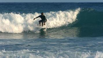 Surfer rides wave, slow motion video