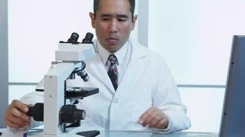 Asian scientist uses microscope and computer