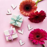 flores de gerbera y cajas de regalo sobre un fondo rosa foto