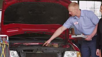 Mechanic in auto repair shop works with customer video