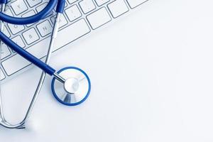 Stethoscope on computer keyboard on white desk Online health care or telemedicine concept Medical background Top view Copy space photo
