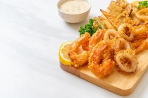 mariscos, camarones y calamares fritos, con mezcla de vegetales - estilo de comida poco saludable foto