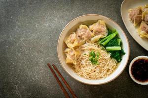 Egg noodles with pork wonton soup or pork dumplings soup and vegetable - Asian food style photo