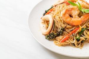 fideos chinos salteados con albahaca, chile, camarones y calamares - estilo de comida asiática foto