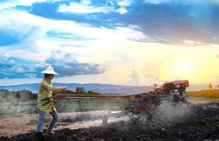 Woman farmer using the walking tractor to plow for rice plant in rainy photo