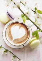 Coffee with a heart shaped pattern and sweet macaroons desserts photo