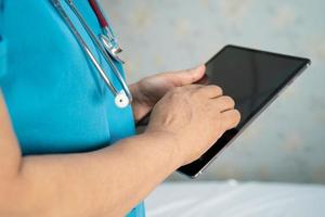 Doctor holding digital tablet to search data for treat patient in nursing hospital ward photo