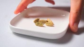 A hand holding white small tray with cardamom photo