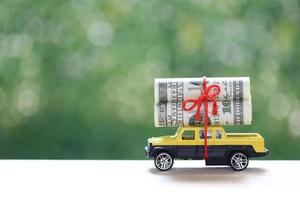 Miniature car and banknotes on nature green background photo