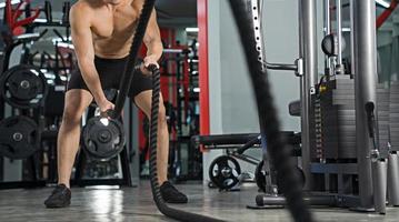 Man working out with battle ropes at gym Functional training  Sport fitness training photo