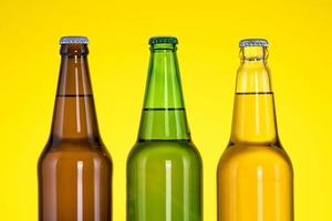 Group of Three bottles of beer isolated on yellow background photo