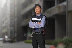 hombre de seguridad de pie al aire libre cerca del gran edificio foto