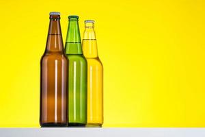 Group of Three bottles of beer isolated on yellow background photo