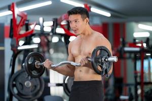 Sporty man training with a heavy barbell at the gym photo