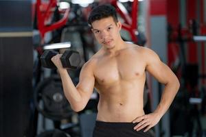 Sporty man training with dumbbell in gym