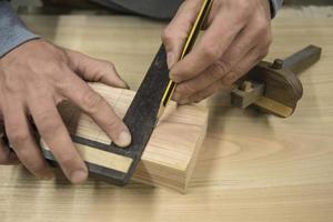 a joiner with a pencil and a square marks the workpiece photo