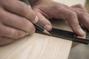 el carpintero marca la pieza de trabajo con un lápiz de carpintería