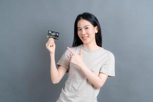 Portrait of a lovely young Asian woman showing credit card photo