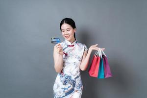 Mujer asiática vistiendo traje tradicional chino con bolsa de compras y tarjeta de crédito foto