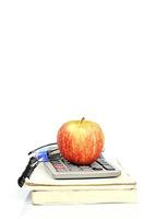 Manzana roja en la pila de libros y calculadora con gafas foto