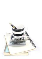 Fountain pen in coffee cup and calculator on book stack photo