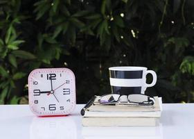 Despertador y notas de libro con taza de café y vasos. foto