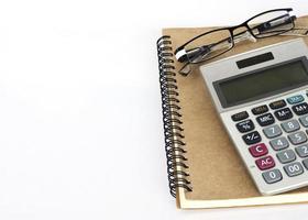 Calculator and glasses with book notes on white background photo