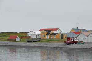 Houses and boat in front of the beach in Vigur island, Iceland photo