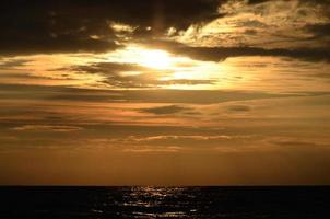 orilla del mar cielo tonos naranjas nubes y olas del mar hermosa naturaleza puesta de sol brillante agua oscura foto