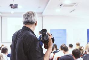 Senior cameraman recording business conference presentation photo