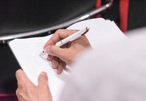 Closeup view of business person taking notes at business conference photo