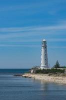 seascape with beautiful white lighthouse on blue sky background photo