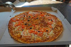 Large pizza in a cardboard box on a wooden table photo