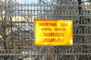 A sign reading restricted area on a metal fence photo