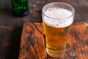 Jarras de cerveza y botellas de cerveza en una mesa de madera foto