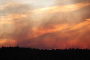 Capas translúcidas de humo y nubes en el cielo al atardecer durante un incendio forestal foto