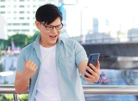 Portrait handsome man is using a smartphone and appears happy There is a building background and modern buildings photo